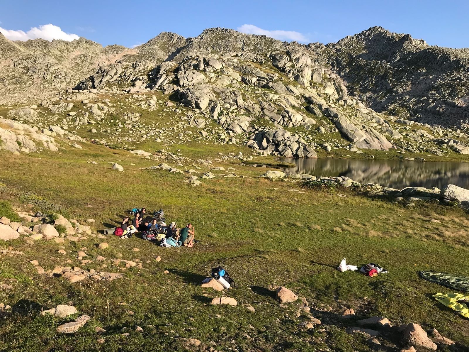 A group of people camping in a mountainous area with a lake.