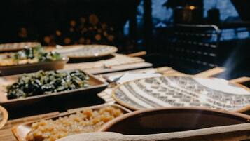 Una mesa con varios platos, incluyendo un tazón de sopa y diferentes acompañamientos, en una habitación poco iluminada con paredes de ladrillo.
