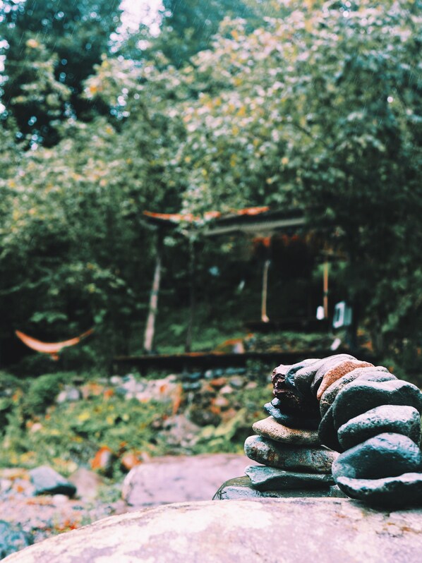A stone arrangement in a natural setting with a wooden structure in the background. - Sana Yasam Koyu (Findikli)