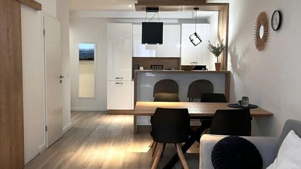 A modern apartment with a dining area, kitchenette, and a living room with a sofa and coffee table. - Hotel La Fleur (Ueberlingen)