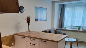 A modern kitchen with a wooden countertop, a built-in stove, and a dining area with a glass table and chairs. - Hotel La Fleur (Ueberlingen)