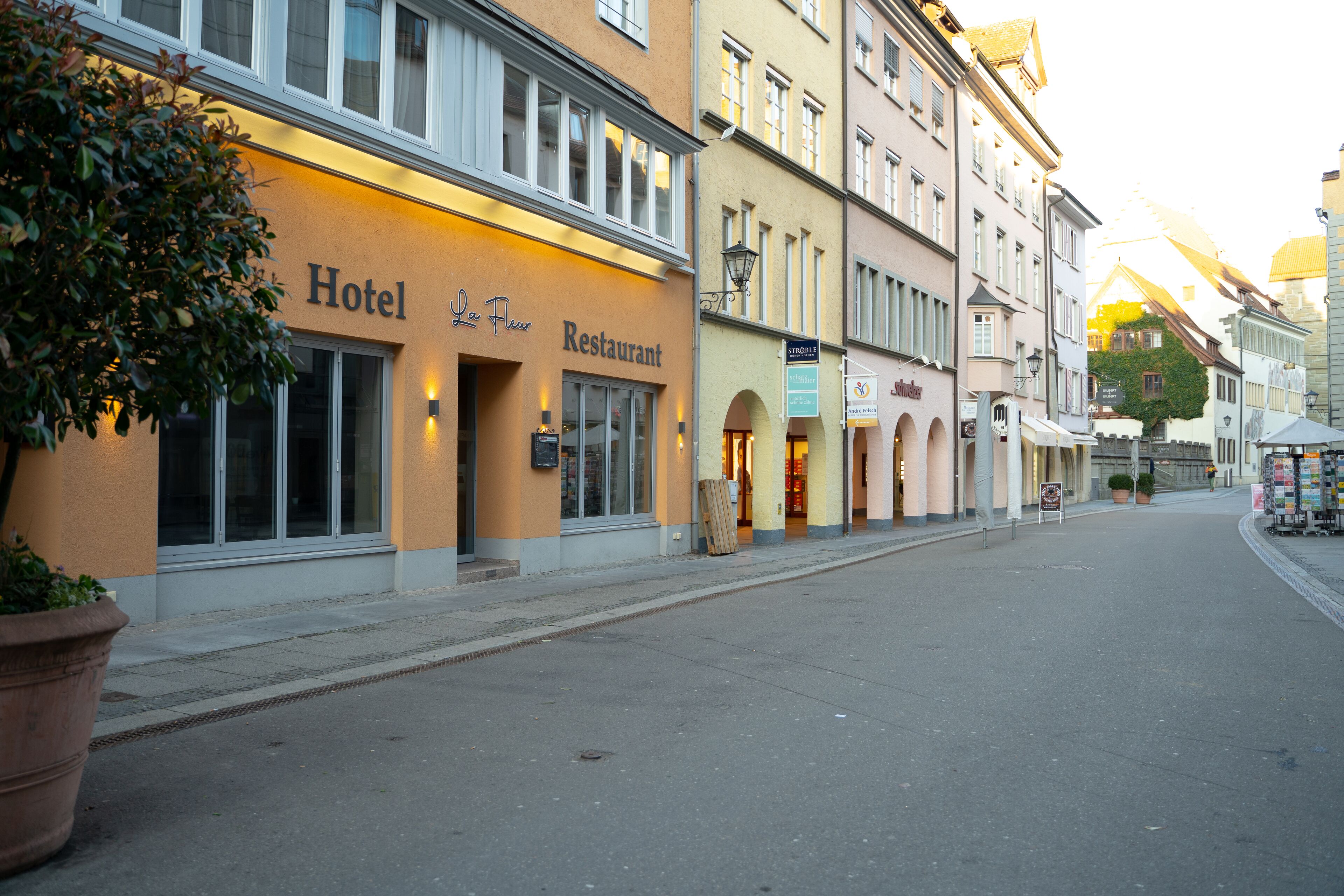A hotel with a restaurant on the ground floor, featuring a large window and a signboard.