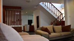 A living room with a sofa, a coffee table, and a staircase. - Poonsiri Private Pool Villa Aonang (Krabi)