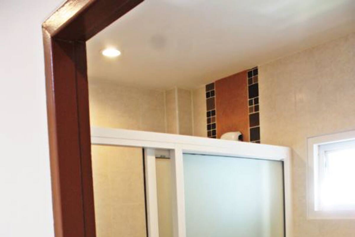A bathroom with a glass shower enclosure, a toilet, and a sink.