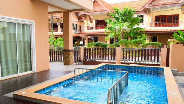 A swimming pool with a wooden deck and a glass door leading to a covered area. - Poonsiri Private Pool Villa Aonang (Krabi)