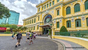 A historic yellow building with green shutters and ornate details, surrounded by pedestrians and palm trees. - Ivy House Serviced Apartment (Ho Chi Minh City)
