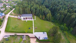 Vue aérienne d’une propriété comprenant un grand bâtiment, un espace de stationnement et une forêt environnante.