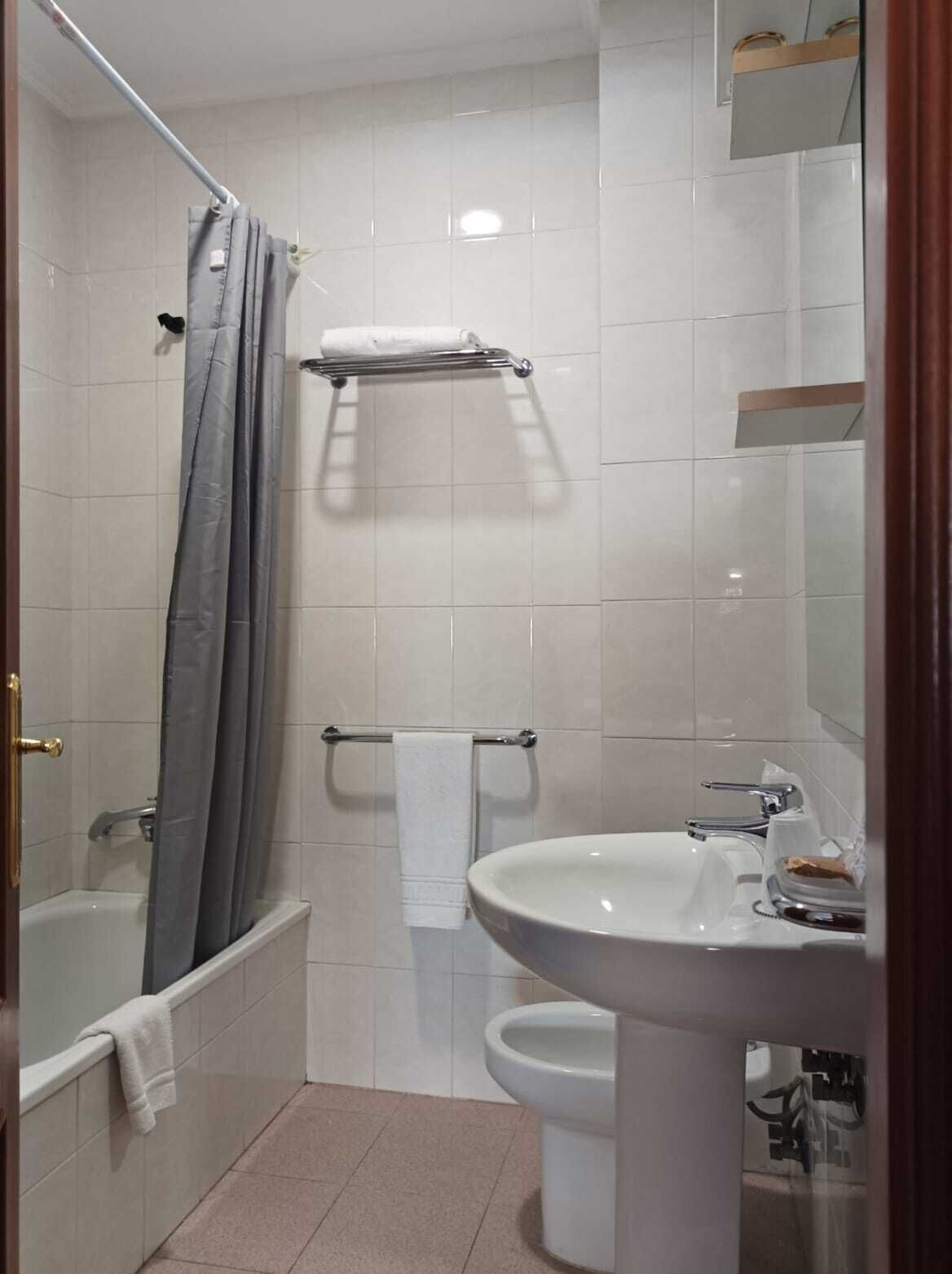 Un baño con bañera, inodoro, lavamanos y cortina de ducha.