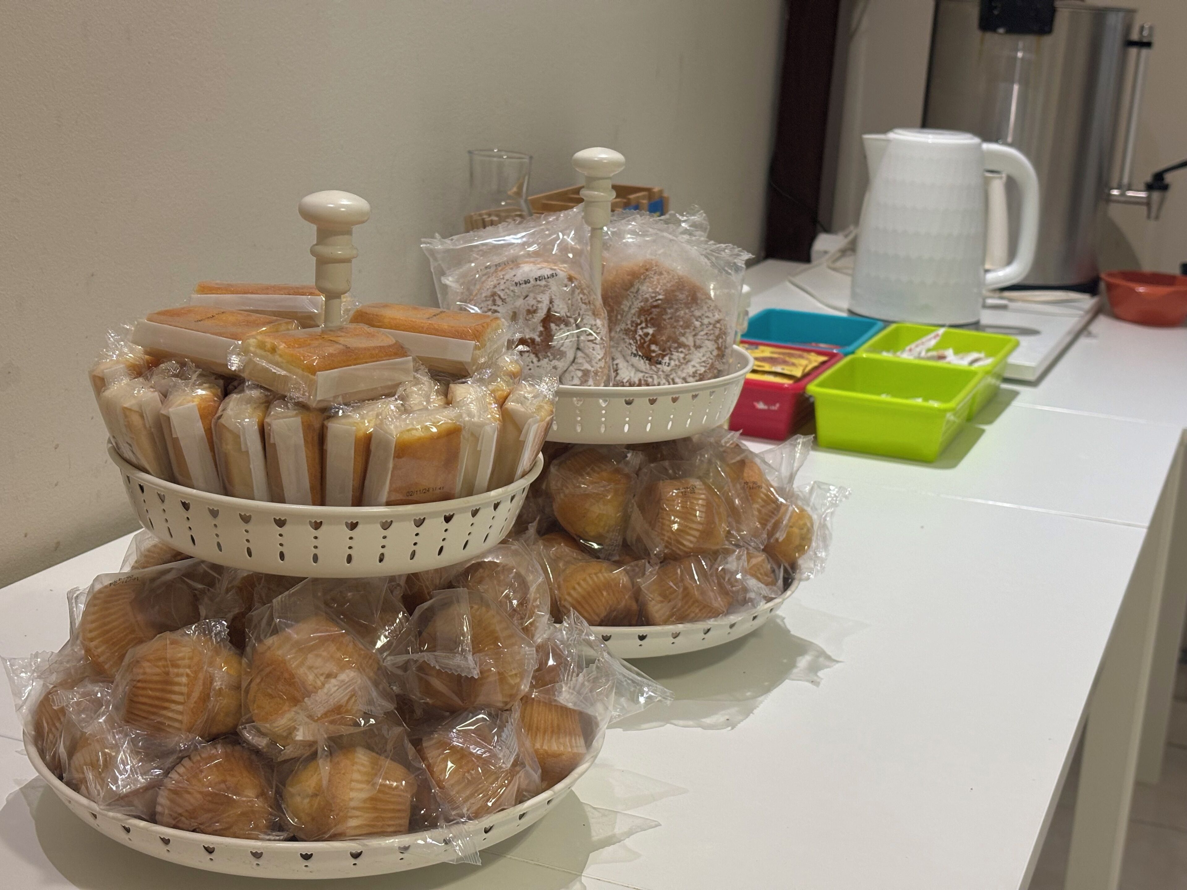 Una mesa de buffet con diversos alimentos, incluyendo pasteles y dulces, dispuestos en cestas y platos.