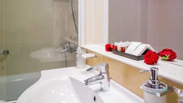 A modern bathroom with a white sink, a glass-enclosed shower, and a vanity with a mirror and a towel rack.
