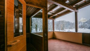 A wooden interior with a view of a snowy landscape and a castle in the distance. - Hotel Trakoscan (Bednja)