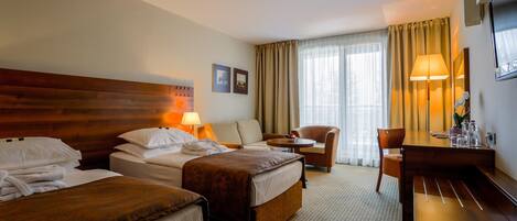A hotel room with two beds, a desk, a chair, and a large window with curtains.