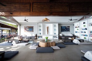 A modern interior with a central seating area, bookshelves, and ceiling fans. - Samahita Retreat Koh Samui - SHA Plus (Koh Samui)