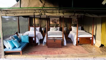 A four-poster bed with a canopy, a sofa with cushions, and a rug in a tent-style room.