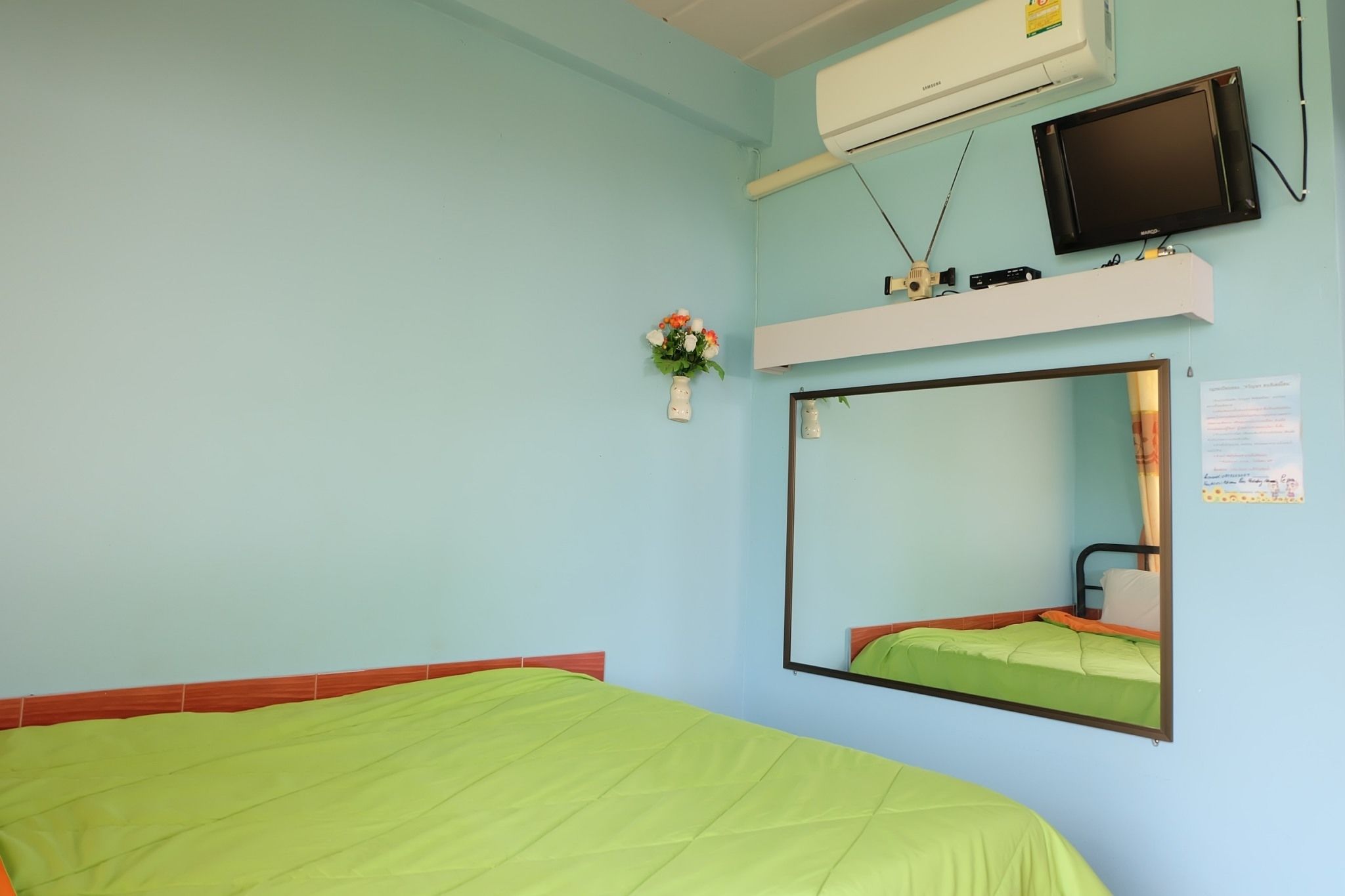 Una habitación con cama, un espejo grande, aire acondicionado y televisor.