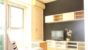 Una sala de estar con un sofá, un televisor y estantes empotrados.