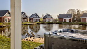 A residential area with houses, a hot tub, and a calm water body. - Europarcs IJsselmeer (Medemblik)