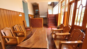 Una larga mesa de madera con sillas, una escalera y vistas al exterior.