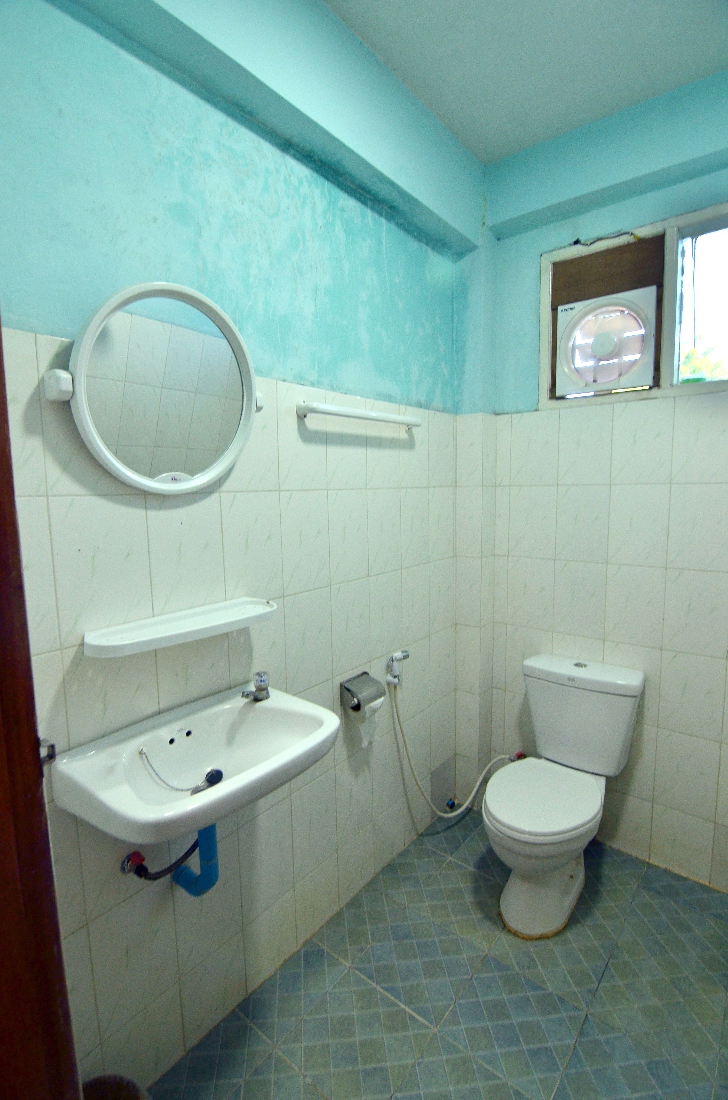 Un baño con lavamanos, espejo, inodoro y ventana.