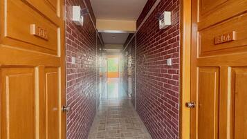 A hallway with wooden doors labeled 303 and 304, brick walls, and a patterned floor.