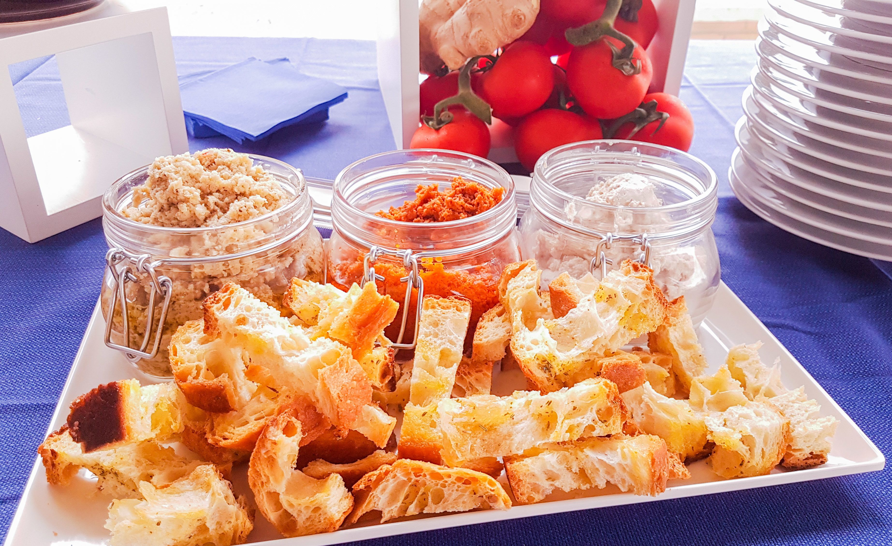 A white plate with toasted bread and three glass jars of spreads.