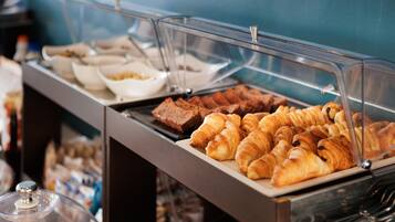 A buffet with various baked goods including croissants and brownies.