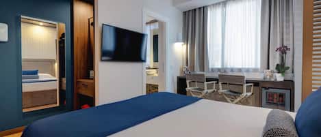 Una habitación de hotel con una cama grande, un escritorio, un televisor y una ventana con cortinas.