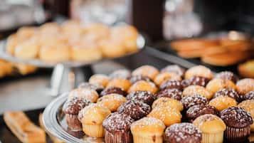 Una exhibición de diversos productos horneados, como muffins y pasteles, dispuestos en bandejas.