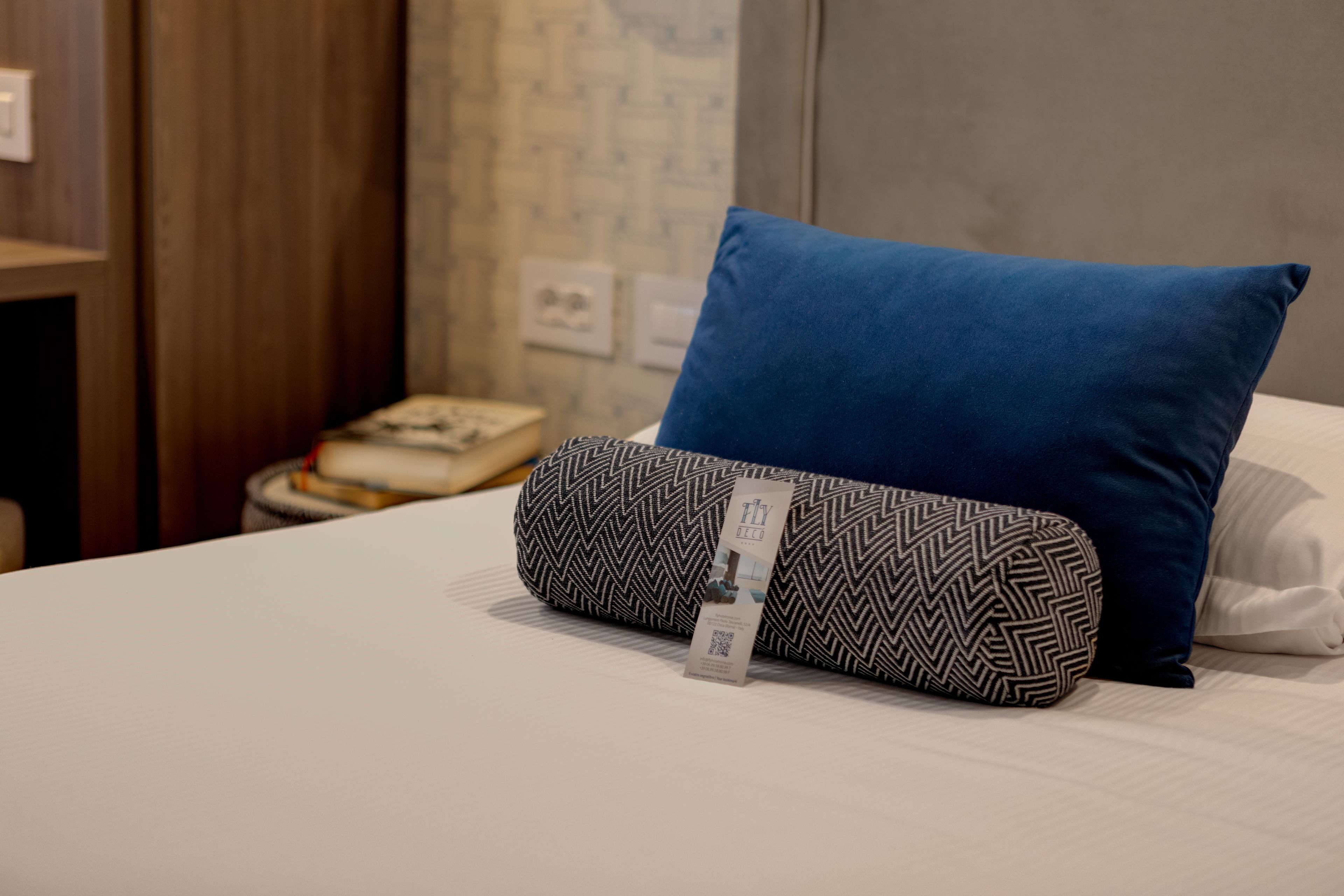 A neatly made bed with a blue pillow and a patterned pillow.