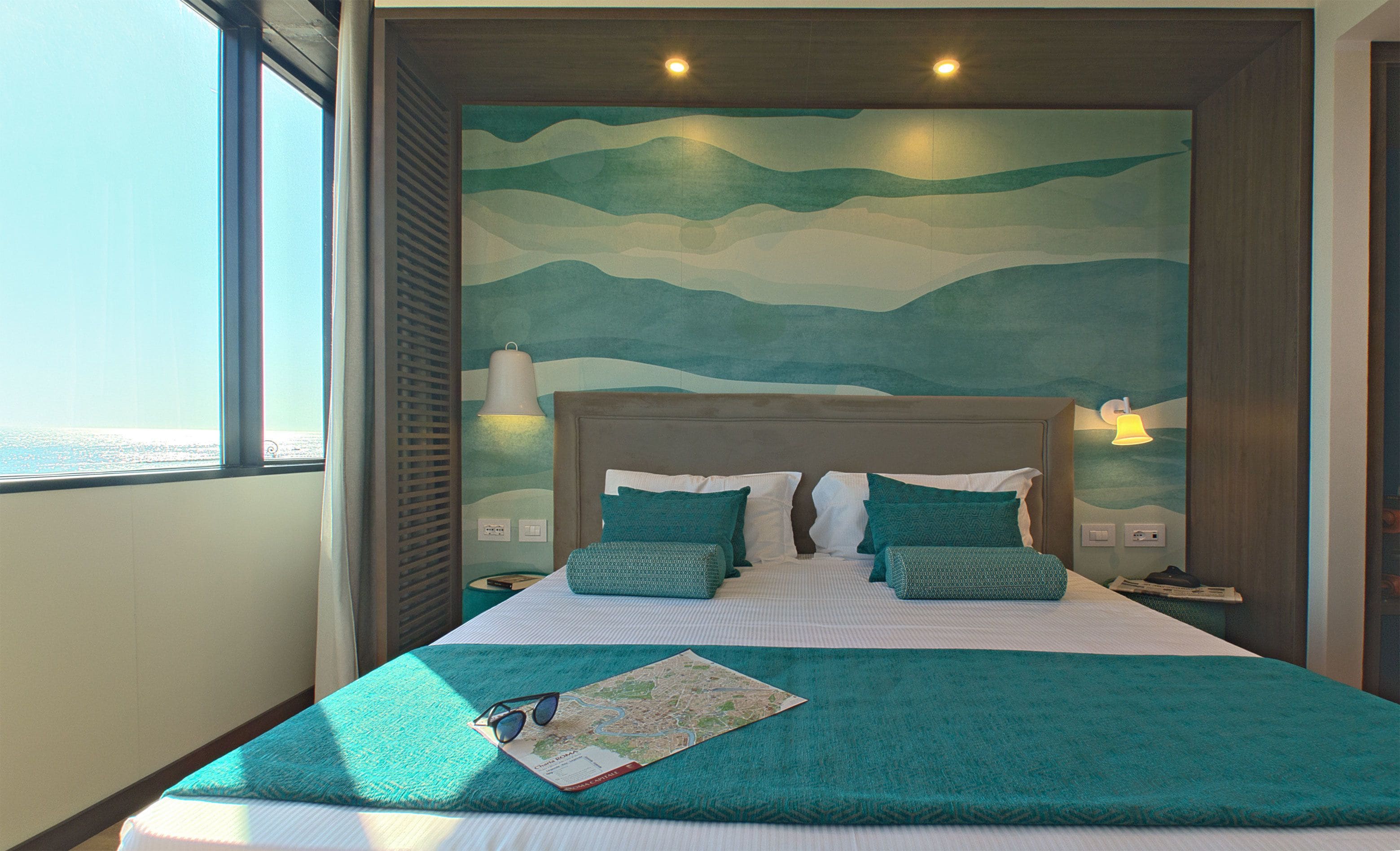 A hotel room with a large bed, a view of the sea, and a map on the bed.