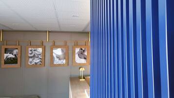 Una habitación con techo de diseño tipo cuadrícula, pared con cuadros enmarcados y un separador azul a rayas.