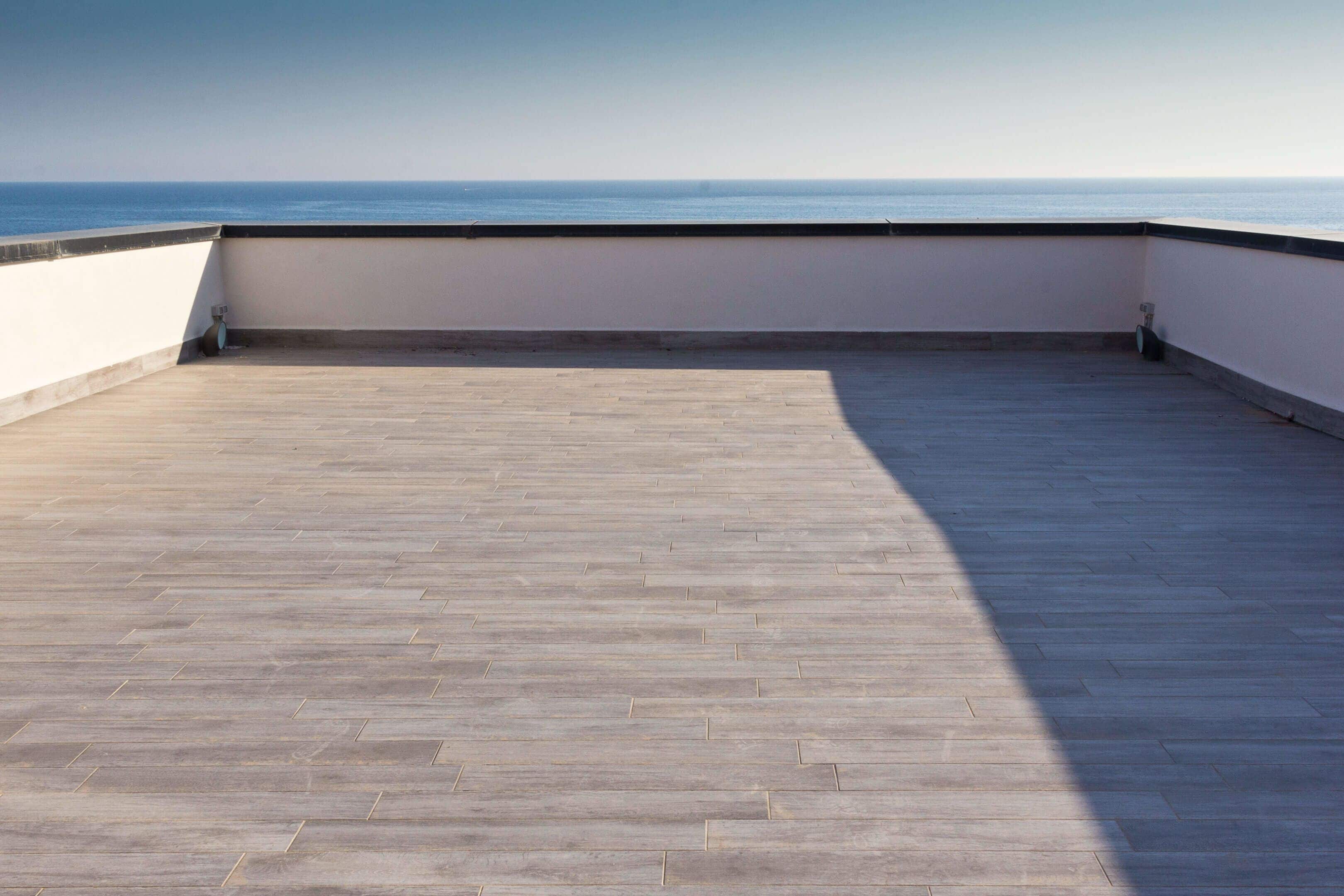 An empty rooftop terrace with a view of the sea.