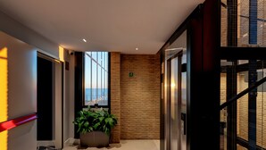 Un pasillo moderno con una planta, un revestimiento de madera y un ascensor de vidrio.