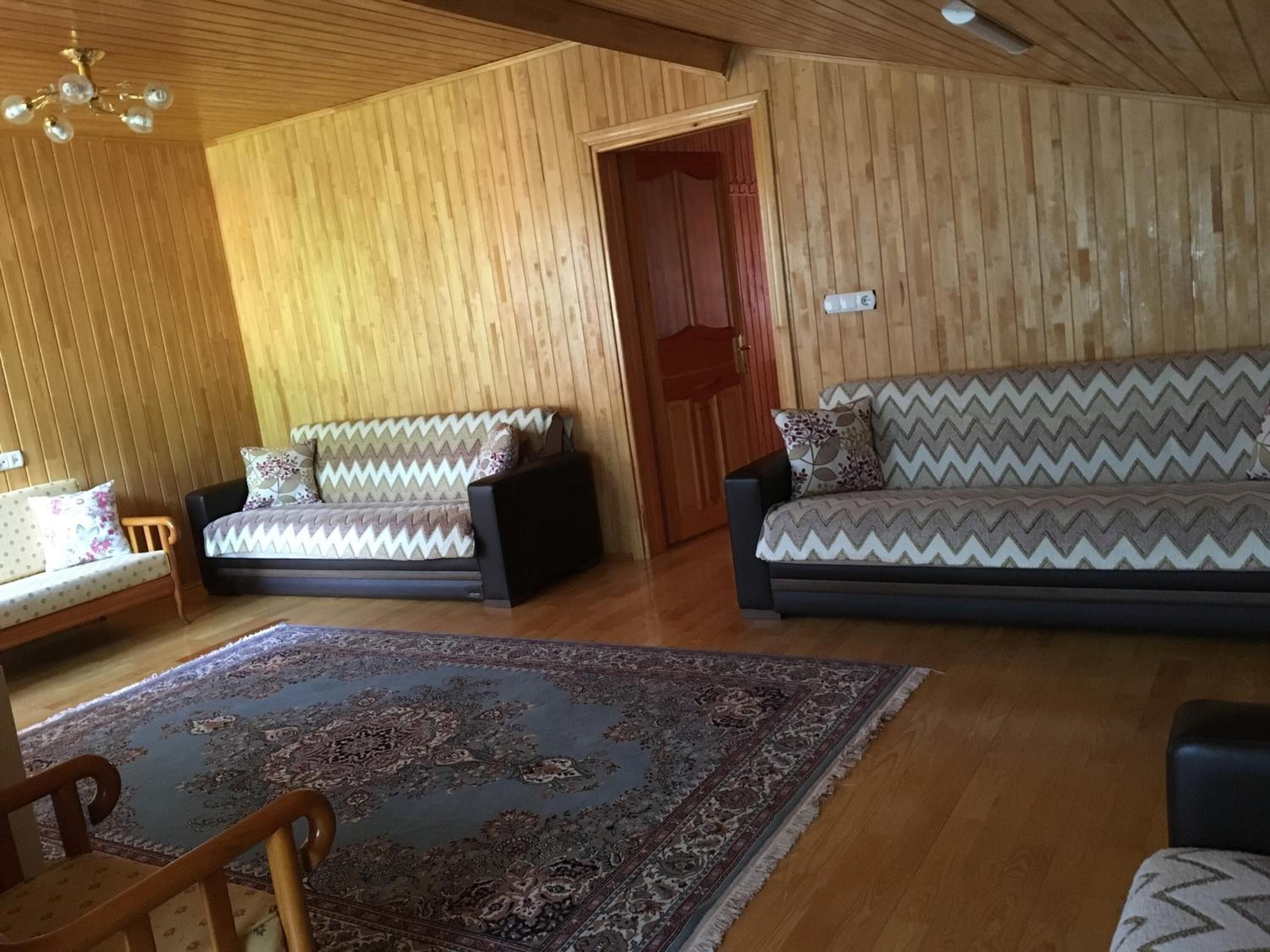 Una sala acogedora con dos sofás, un tapete estampado y techo de madera.