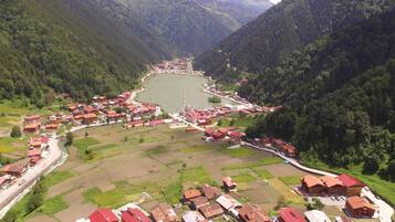 Uma aldeia com um lago central, rodeada por colinas arborizadas.