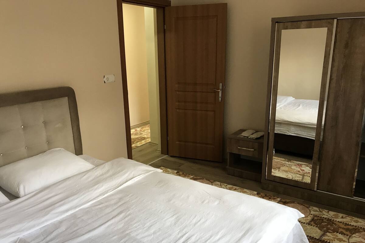 A bedroom with a bed, a wardrobe, and a mirror.
