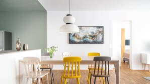 A modern dining area with a wooden table, four chairs, and a hanging pendant light. - Bodensee Apartment Fischbach (Friedrichshafen)