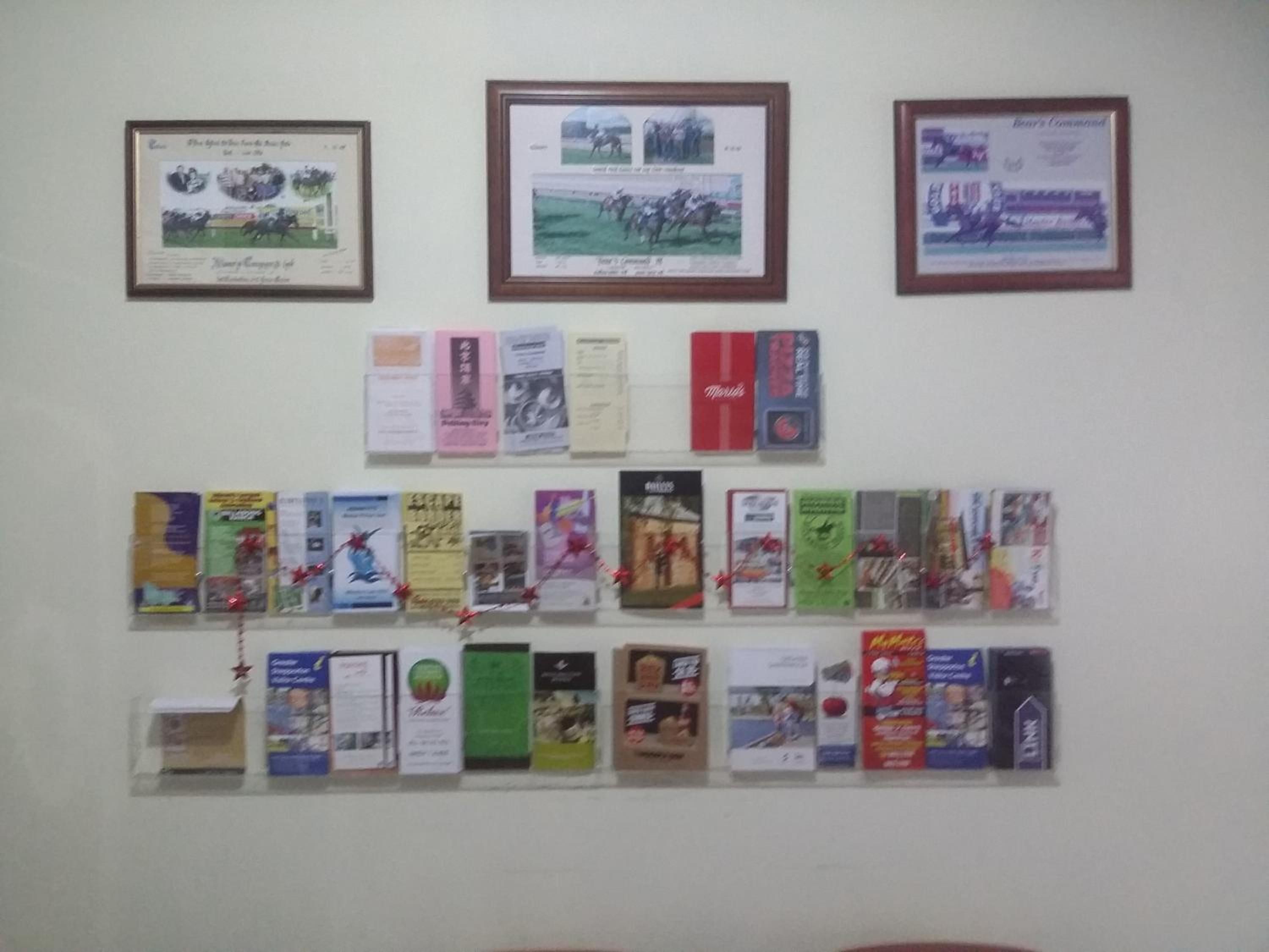 A wall with framed certificates and a collection of books.