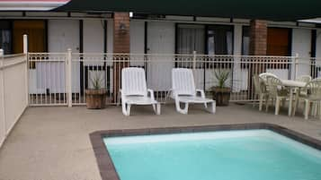 Una piscina al aire libre, sillones reclinables de piscina