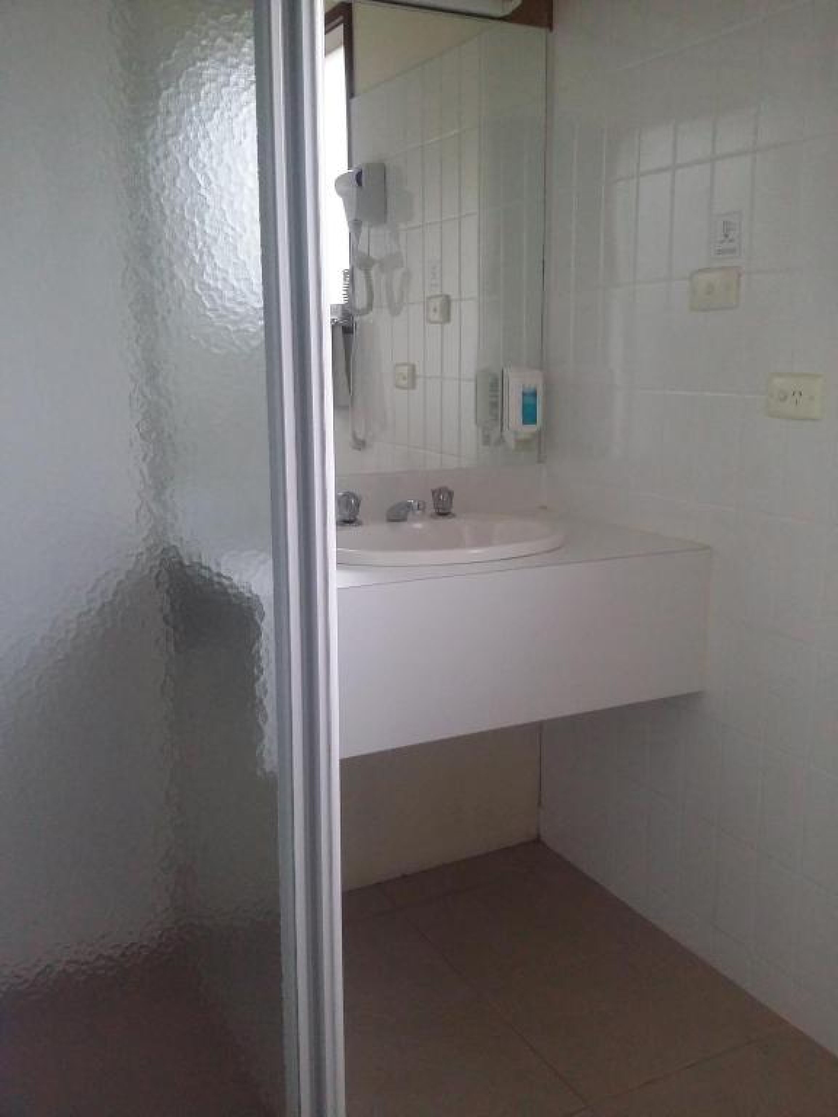 A bathroom with a white sink, a mirror, and a shower area.