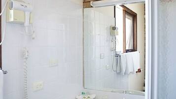 Une salle de bain avec un lavabo blanc, un miroir, un sèche-cheveux et une douche.