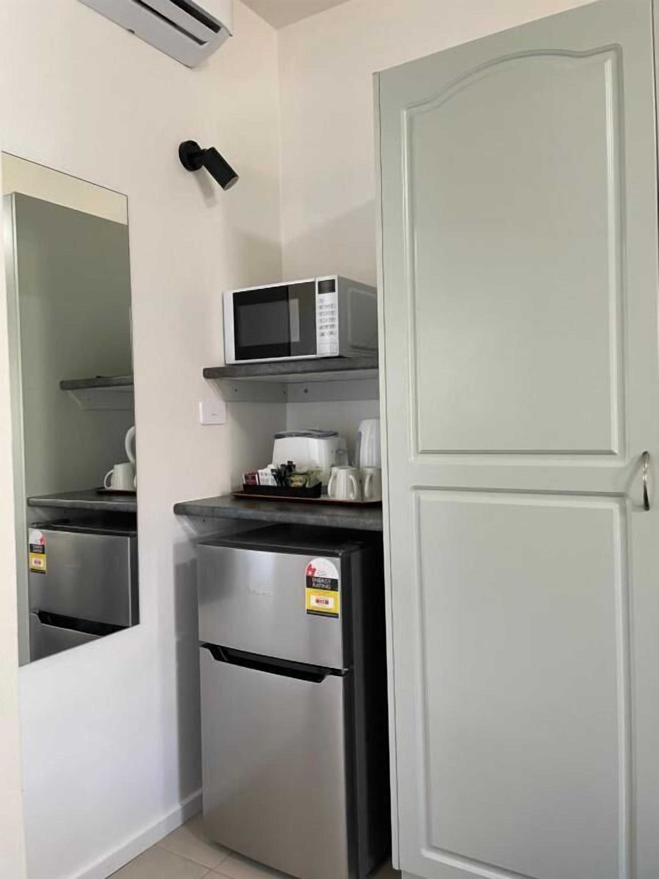 A compact kitchenette with a microwave, a coffee maker, and a refrigerator.
