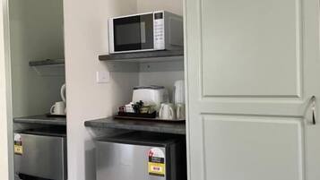 A compact kitchenette with a microwave, a coffee maker, and a refrigerator.