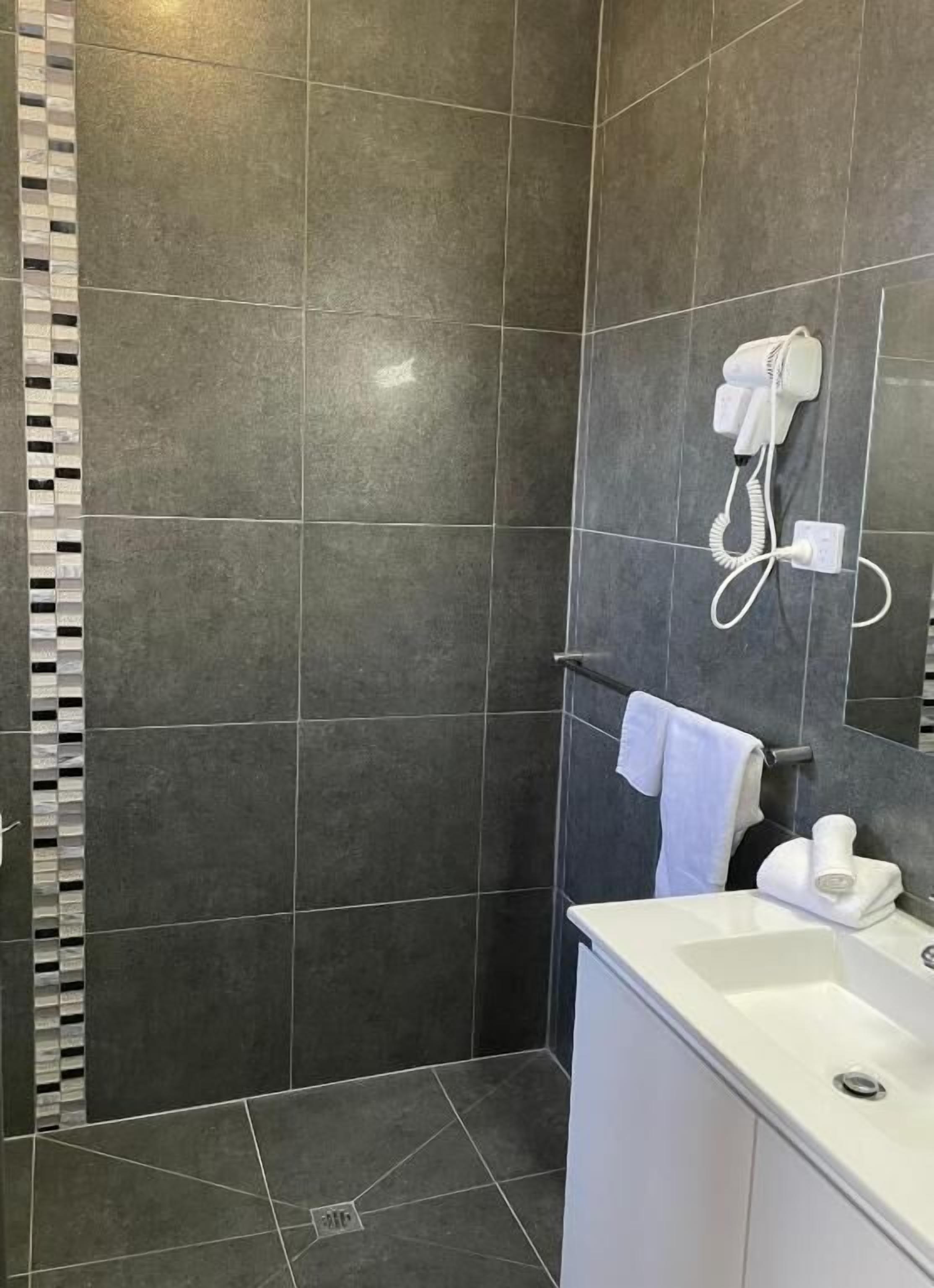 Un bagno moderno con doccia, lavabo e porta asciugamani.