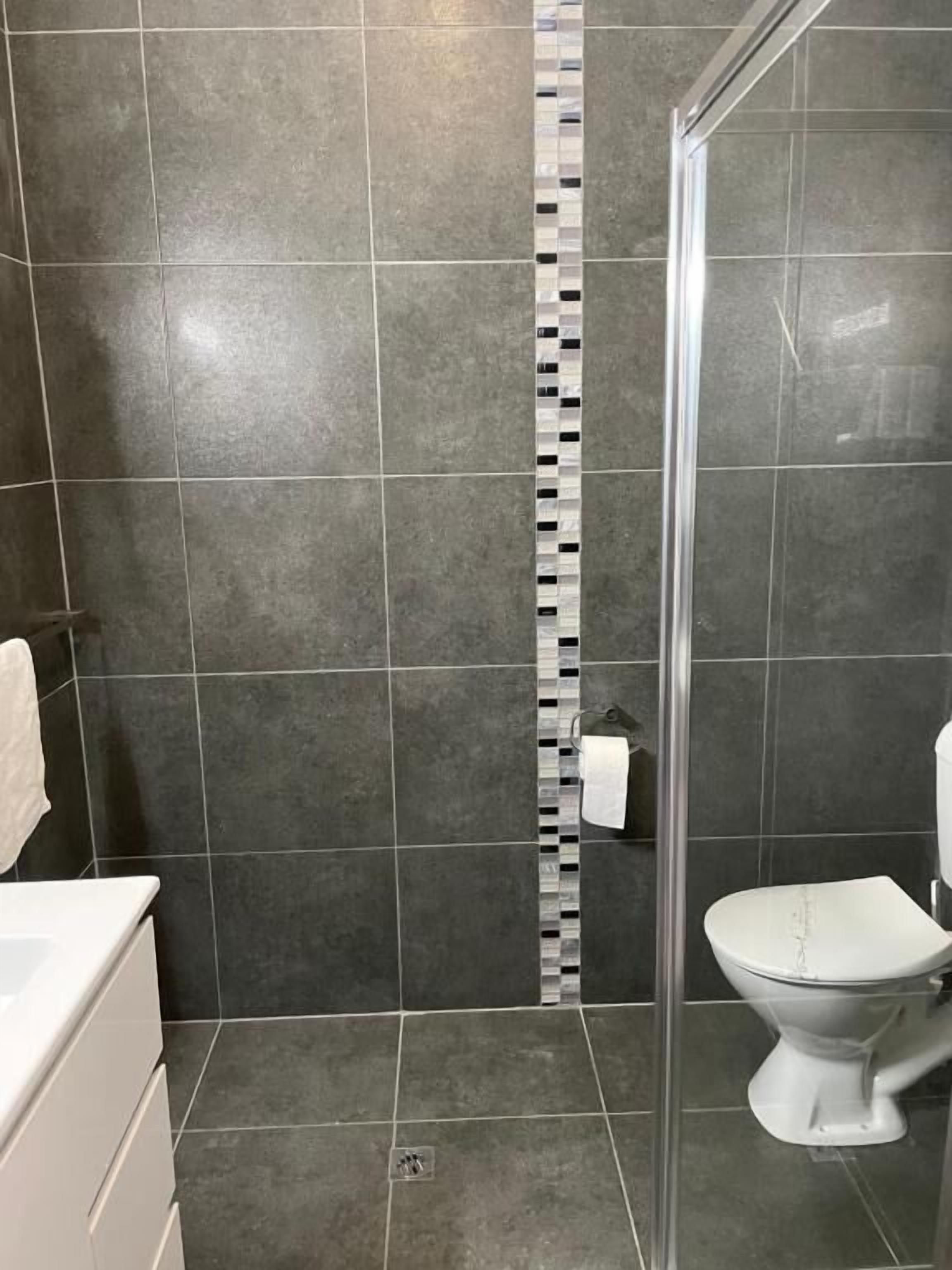 Un baño con cabina de ducha, inodoro y lavabo.