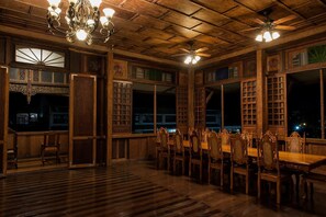 A large wooden dining room with a long table and chairs, ornate wooden paneling, and a chandelier. - Casa Simeon (Bacacay)