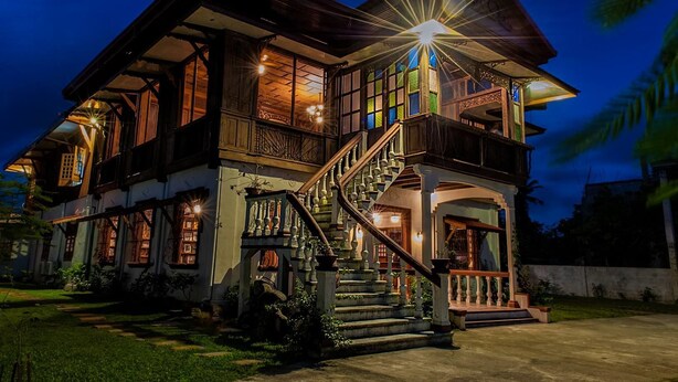 A two-story house with a prominent staircase, large windows, and a well-lit exterior at night. - Casa Simeon (Bacacay)