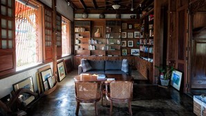 A cozy room with a wooden ceiling, a sofa, two wicker chairs, and a bookshelf filled with books and framed pictures. - Casa Simeon (Bacacay)
