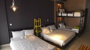 Hotellihuoneessa on kaksi sänkyä, pieni työpöytä ja nurkassa kerrossänky.
