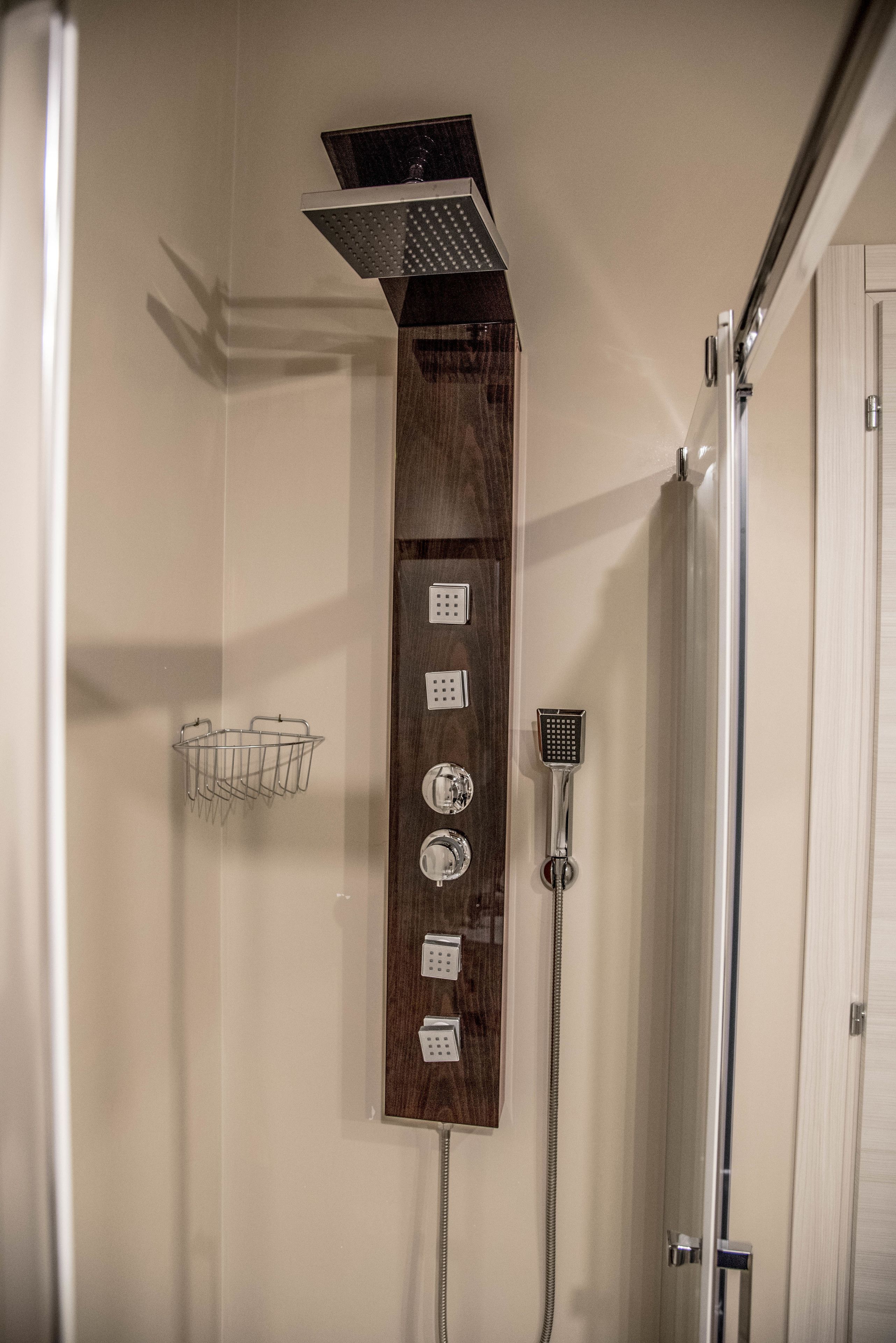 A shower area with a wooden panel, multiple showerheads, and a towel rack.